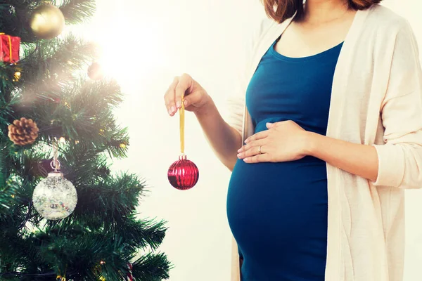 Pregnant woman decorating christmas tree — Stock Photo, Image
