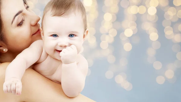 Mère avec bébé sur fond de lumières festives — Photo