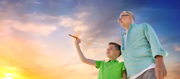 Homem sênior e menino com avião de brinquedo sobre o céu — Fotografia de Stock