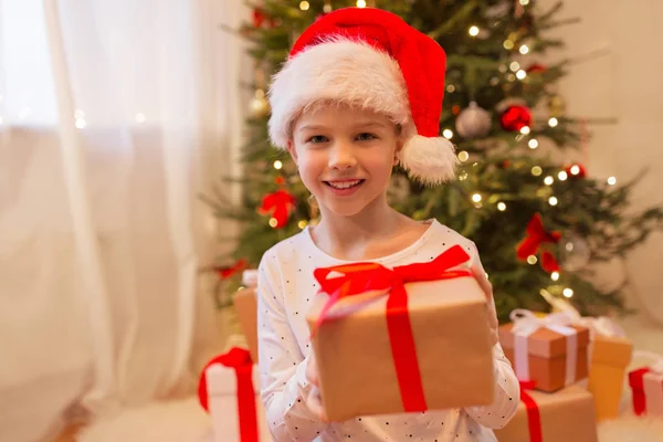 Smiling girl in santa hat with christmas gift — Stock Photo, Image