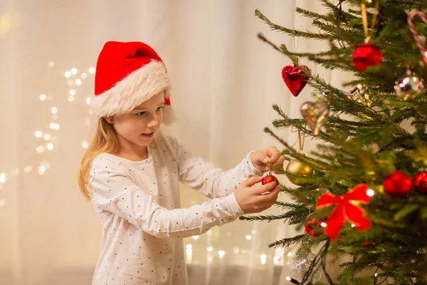 Chica feliz en el árbol de Navidad de decoración de sombrero de santa — Foto de Stock