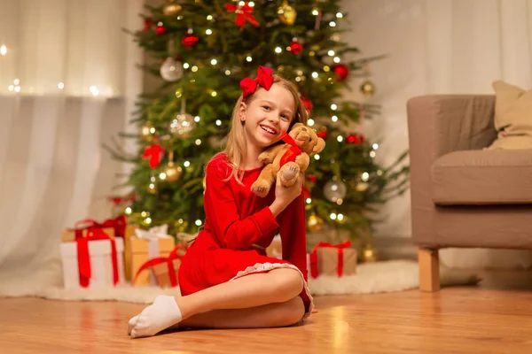 Evde oyuncak ayı sarılma kırmızı elbiseli kız — Stok fotoğraf