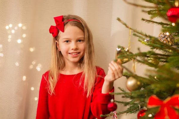 Happy girl in red decorating christmas tree — Stock Photo, Image