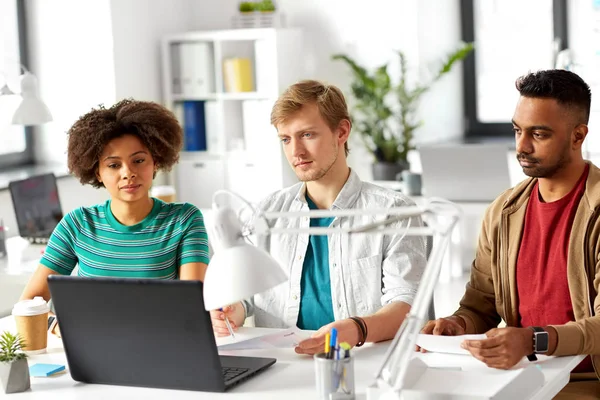Lyckliga kreativa arbetstagare med bärbara datorer på kontor — Stockfoto