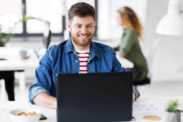 Усміхнений творчий чоловік з ноутбуком працює в офісі — стокове фото