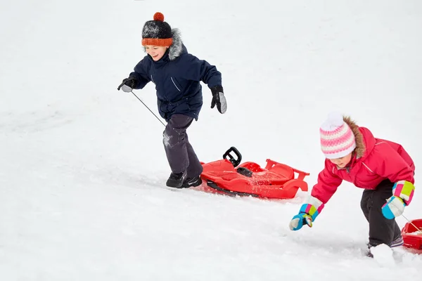 Enfants avec luges escalade colline de neige en hiver — Photo