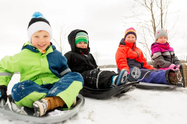 Glada små barn glidande på slädar vintertid — Stockfoto