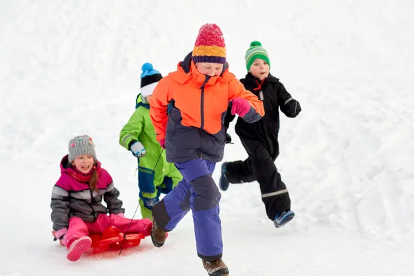 Glückliche Kinder mit Schlitten, die im Winter draußen Spaß haben — Stockfoto