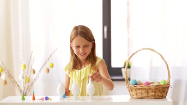 Щаслива дівчина прикрашає великодні яйця вдома — стокове відео