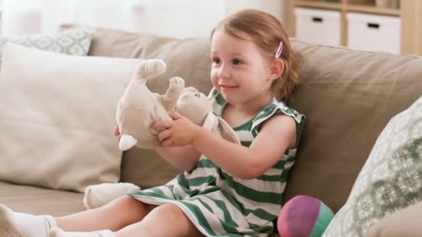 Девочка играет с игрушечным кроликом дома — стоковое видео