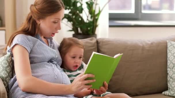 Schwangere Mutter und Tochter lesen Buch zu Hause — Stockvideo