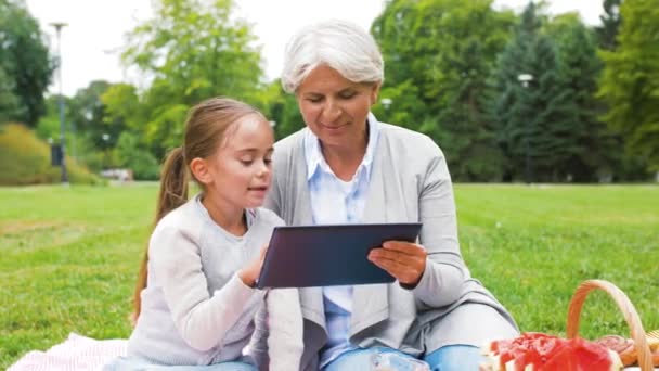 Abuela y nieta con tableta en el parque — Vídeos de Stock