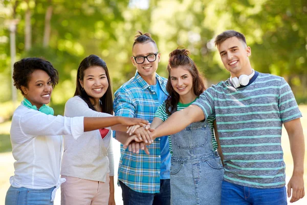 Felices amigos sonrientes apilando las manos en el parque — Foto de Stock