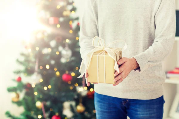 Закройте человека с рождественским подарком дома — стоковое фото