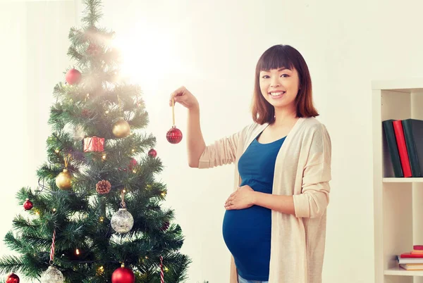 妊娠中の女性が自宅のクリスマス ツリーを飾る — ストック写真