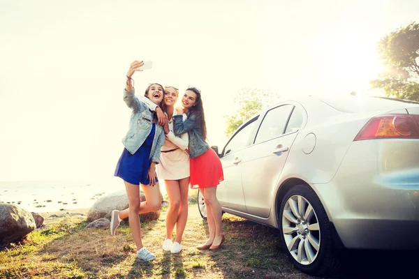 Femmes heureuses prenant selfie près de la voiture au bord de la mer Photo De Stock