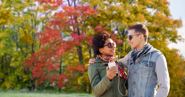 couple listens music by smartphone in autumn park