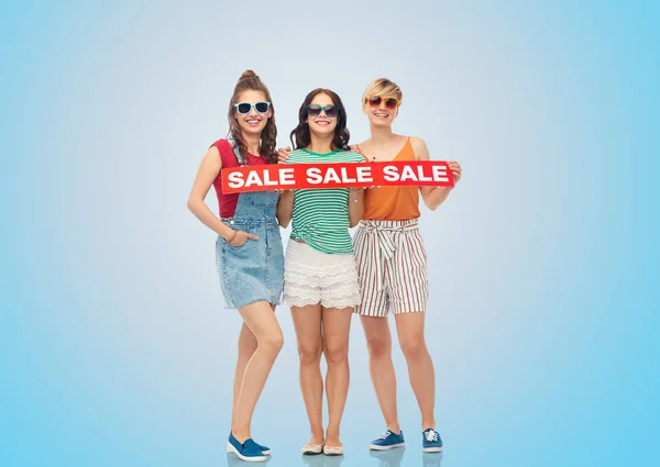 Gelukkig vriendinnen met verkoop spandoek over blue — Stockfoto