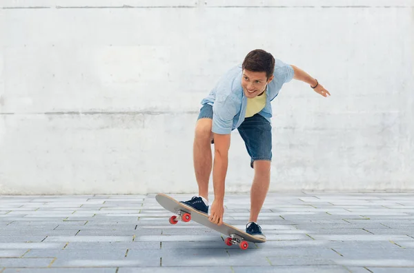 Young man riding skateboard over urban background — Stock Photo, Image