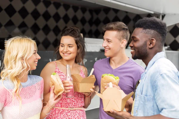 Gelukkige vrienden met dranken eten bij voedsel vrachtwagen — Stockfoto