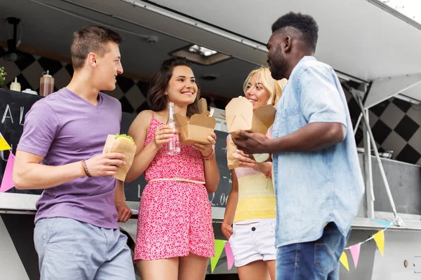 Happy friends with drinks eating at food truck — Stock Photo, Image