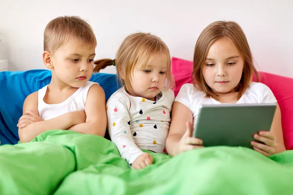 Niños pequeños con tablet pc en la cama en casa — Foto de Stock