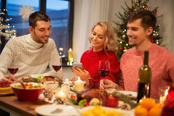 Amis avec téléphone portable fêtent Noël à la maison — Photo