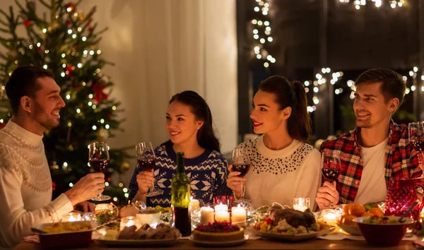 Amigos felices bebiendo vino tinto en la fiesta de Navidad —  Fotos de Stock
