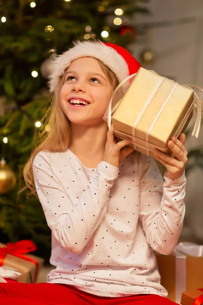 Smiling girl in santa hat with christmas gift — Stock Photo, Image