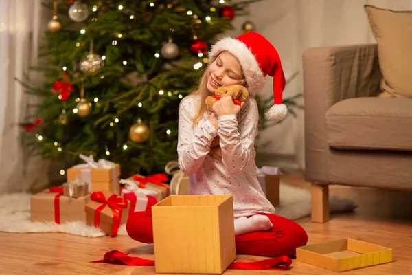 Leende flicka i tomte hatt med julklapp — Stockfoto