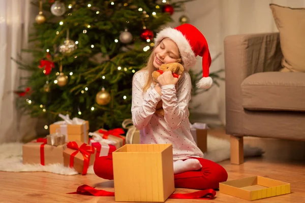 Sorrindo menina em santa chapéu com presente de Natal — Fotografia de Stock