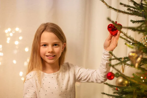 Chica feliz en vestido rojo decorando árbol de Navidad — Foto de Stock