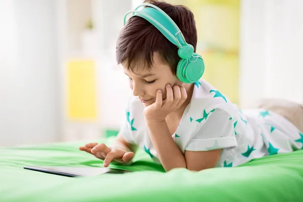 Lachende jongen met tablet pc en hoofdtelefoon thuis — Stockfoto