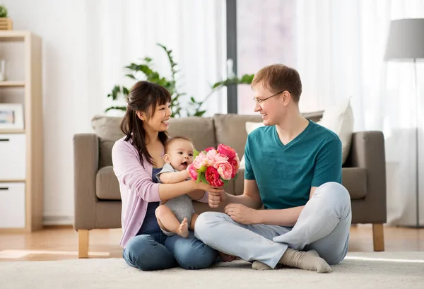 Glückliche Familie mit Blumen und Baby zu Hause — Stockfoto