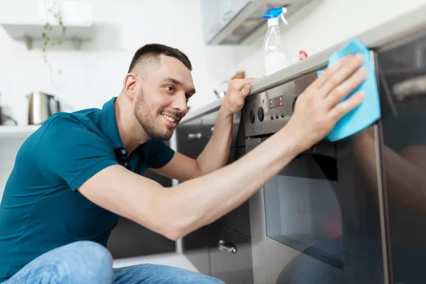 Man met doek schoonmaken van de oven deur huis keuken — Stockfoto