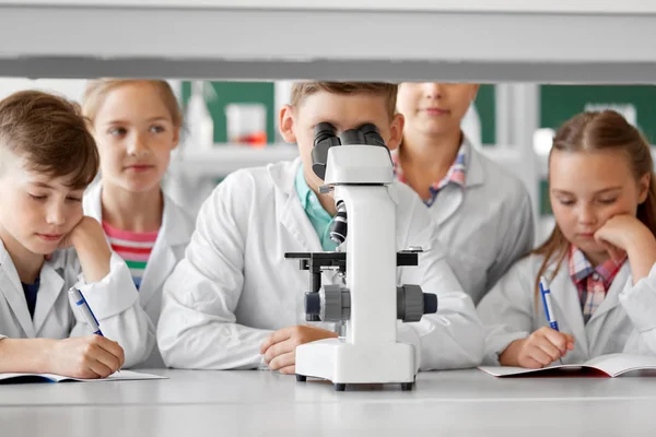 Niños o estudiantes con biología de microscopio en la escuela — Foto de Stock