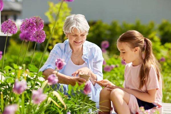 Großmutter und Mädchen säen Blumen im Garten — Stockfoto