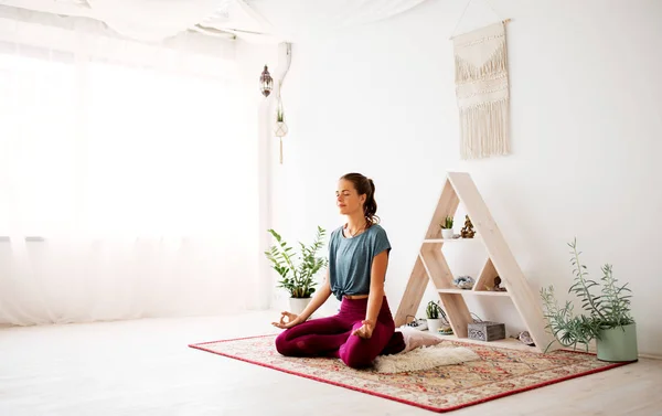 Женщина медитирует в позе лотоса в студии йоги — стоковое фото