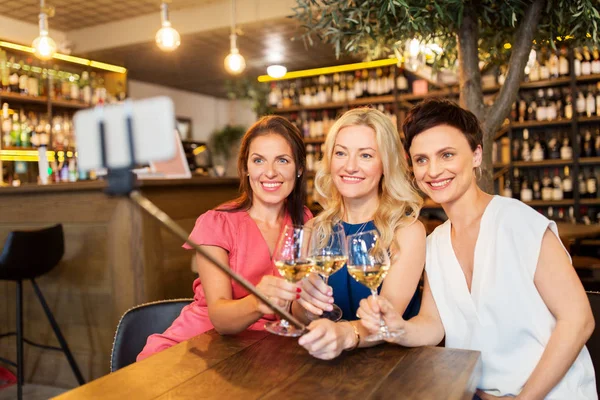 Women taking picture by selfie stick at wine bar — Stock Photo, Image