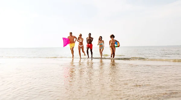 Friends run with beach ball and swimming mattress — Stock Photo, Image
