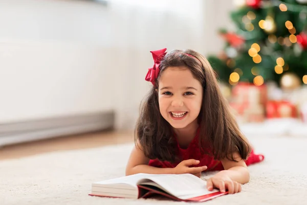 Menina feliz ler livro em casa no Natal — Fotografia de Stock