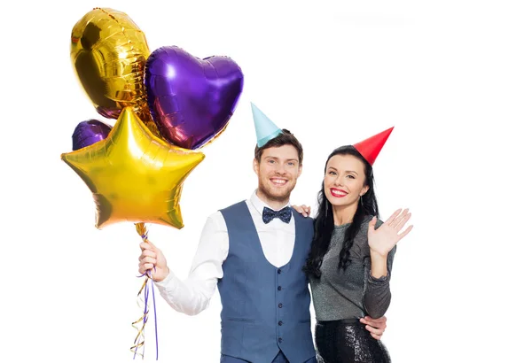 Счастливая пара с шапочками для вечеринок и воздушными шарами — стоковое фото