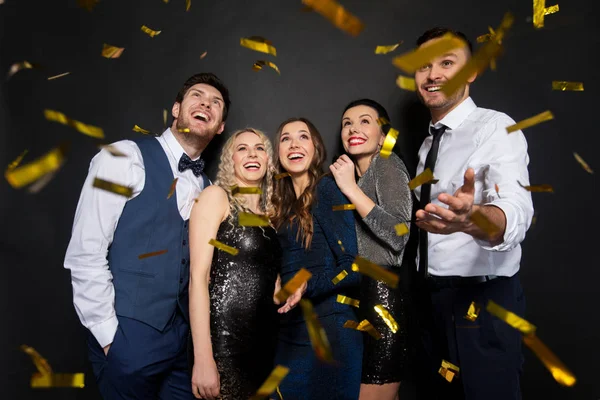 Amigos felizes na festa sob confete sobre preto — Fotografia de Stock