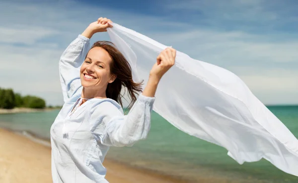Szczęśliwa kobieta z szal macha w wiatr na plaży — Zdjęcie stockowe