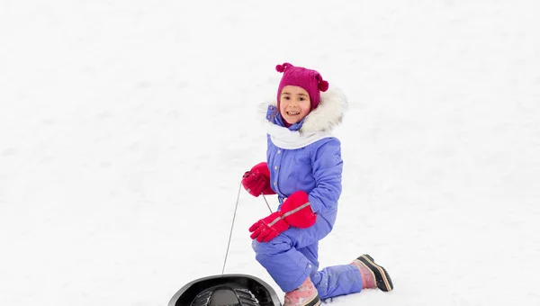 Happy little girl with sled on snow hill in winter — Stock Photo, Image