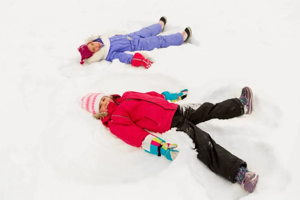 Happy little girls making snow angels in winter — Stock Photo, Image