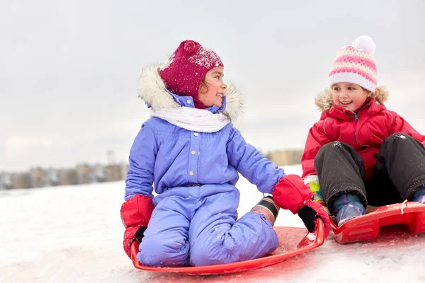 Счастливые девчонки на санках зимой — стоковое фото