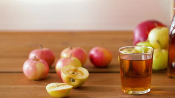 Vidro e garrafas de suco de maçã na mesa de madeira — Vídeo de Stock