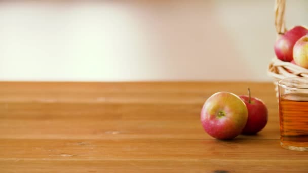 Яблоки в корзине и стаканы сока на столе — стоковое видео
