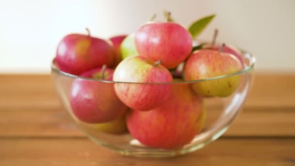 Спелые яблоки в стеклянной чаше на деревянном столе — стоковое видео